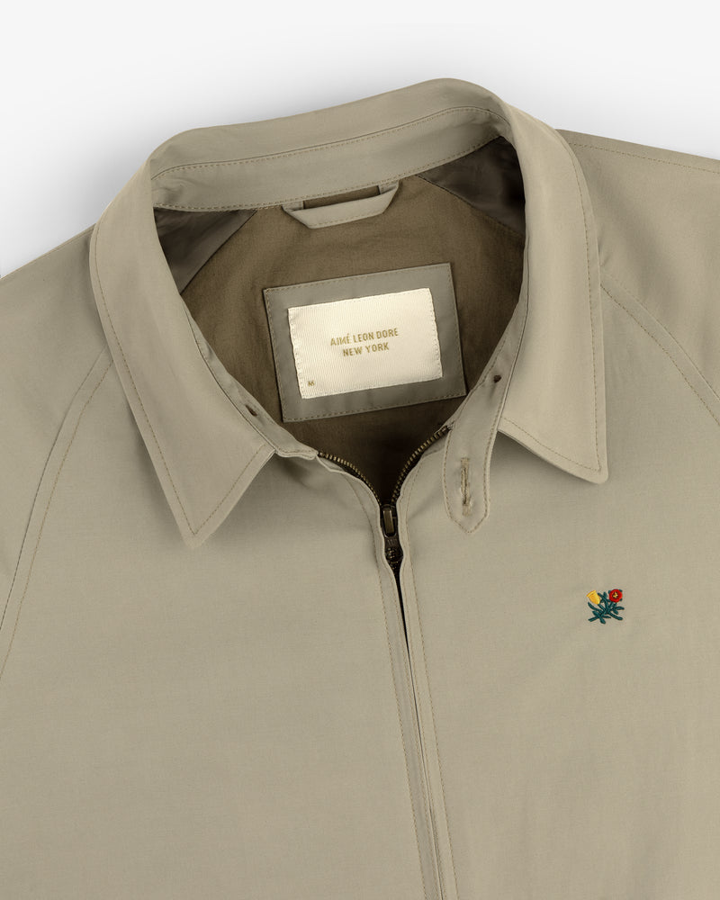 Beige Crest Casual Jacket with zip-up collar, small embroidered flower, and AIMÉ LEON DORE NEW YORK label.