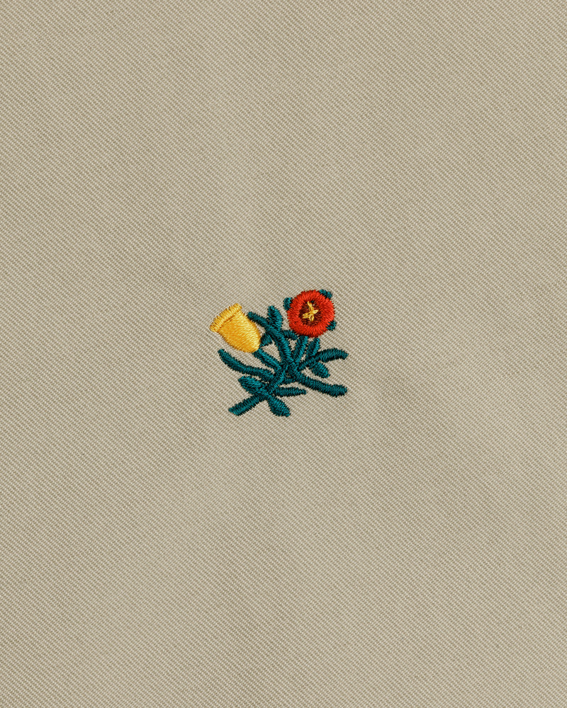Small flower with green stem, yellow bud, and red blossom decorates the Crest Casual Jacket’s beige fabric.
