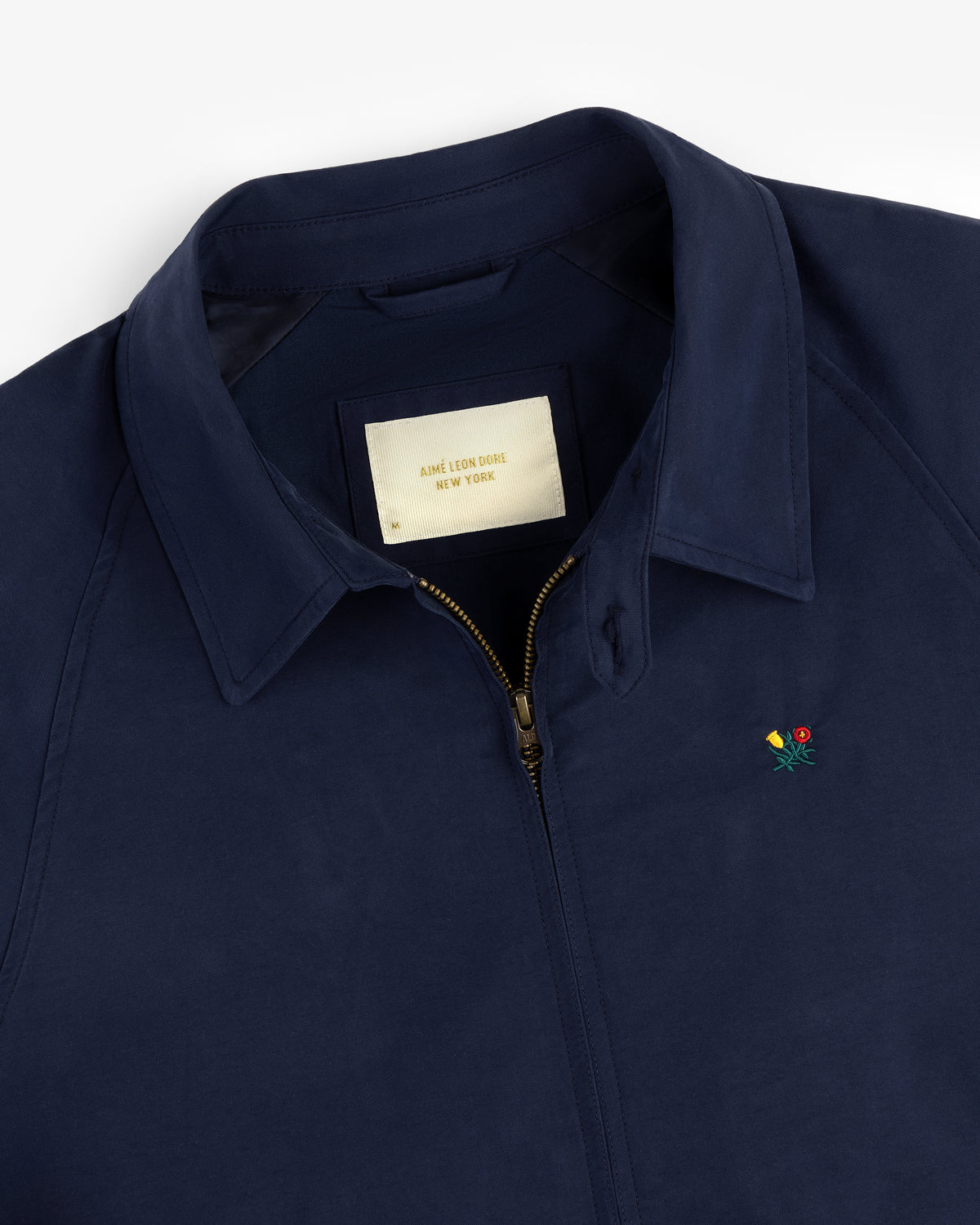 Navy Crest Casual Jacket with zip front, small floral embroidery, and inner Aime Leon Dore New York label.