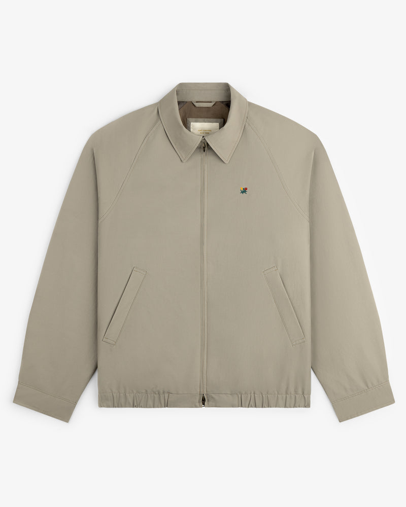 Crest Casual Jacket: light beige zip-up with collar, angled pockets, and small embroidered left chest logo.