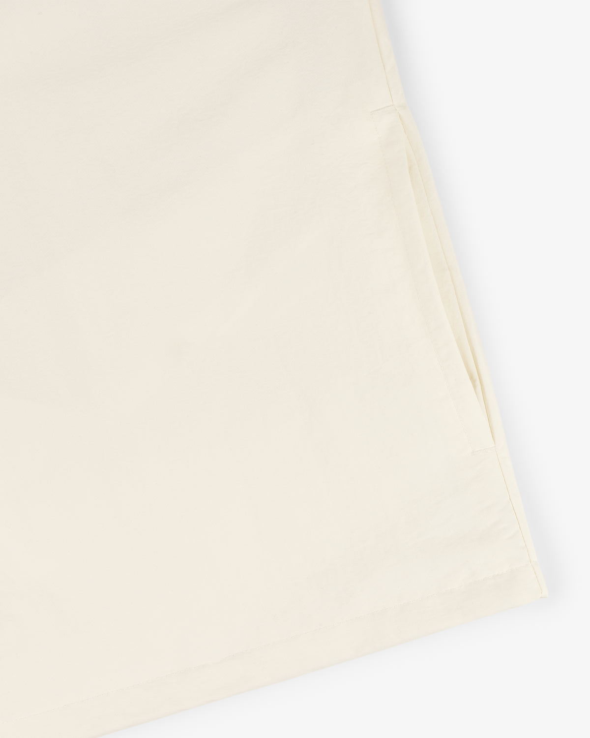 Close-up of the Crest Nylon Half-Zip Pullover in light beige, highlighting a side pocket on a plain background.