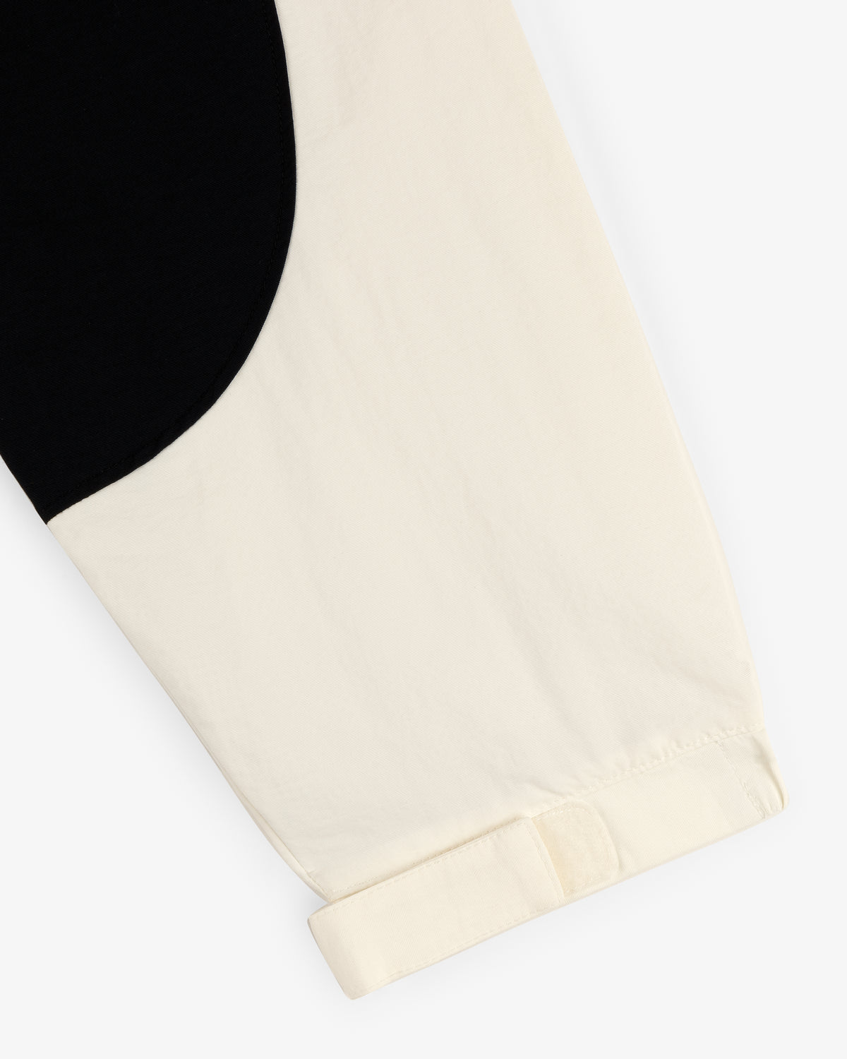 A close-up of the Crest Nylon Half-Zip Pullover, featuring a black and cream color block with a cuffed cream sleeve.