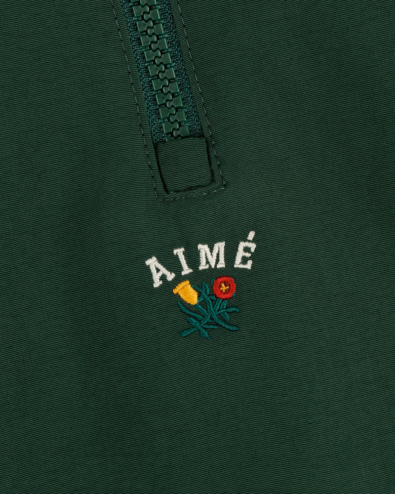 Dark green Crest Nylon Half-Zip Pullover with AIMÉ embroidered above small yellow/red flowers with green leaves.