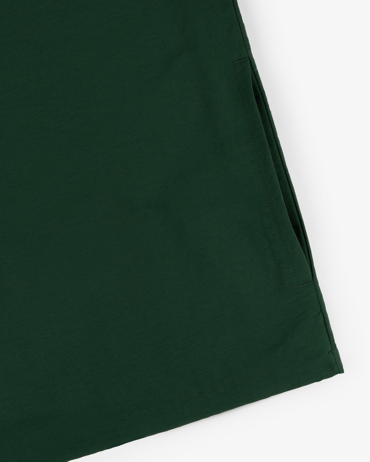 Close-up of the Crest Nylon Half-Zip Pullover in dark green, showing side seam and right pocket opening.