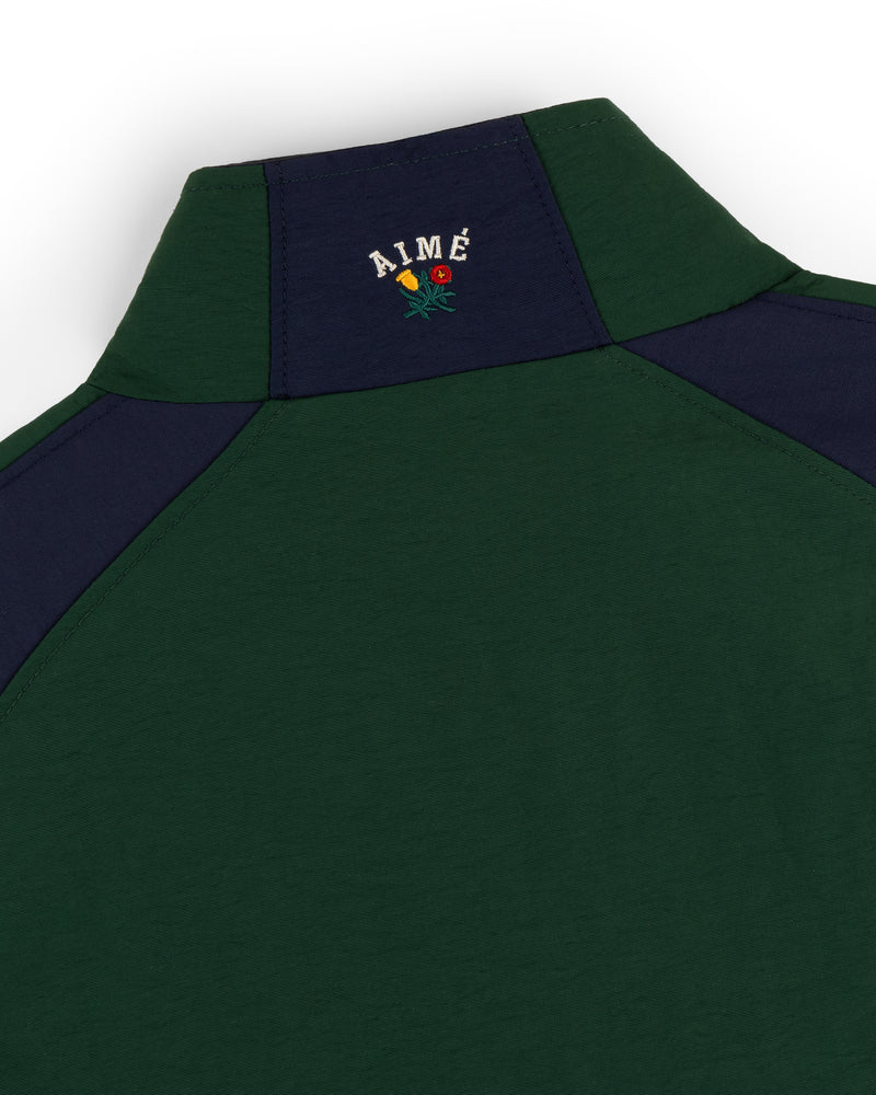 Green and navy Crest Nylon Half-Zip Pullover with AIMÉ and a small embroidered rose on the back near the collar.