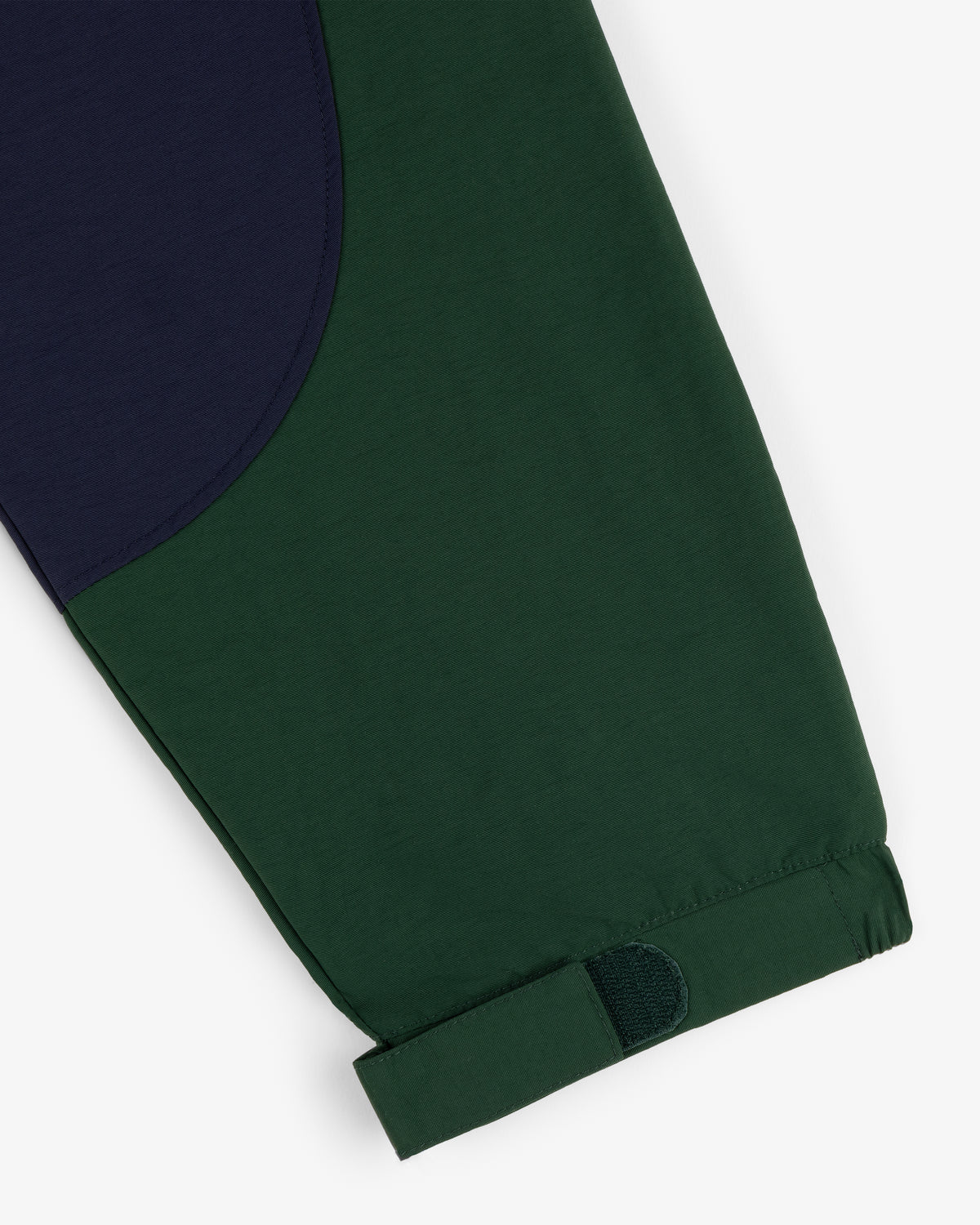 Crest Nylon Half-Zip Pullover in green with a navy patch and adjustable cuff strap, shown on a white background.