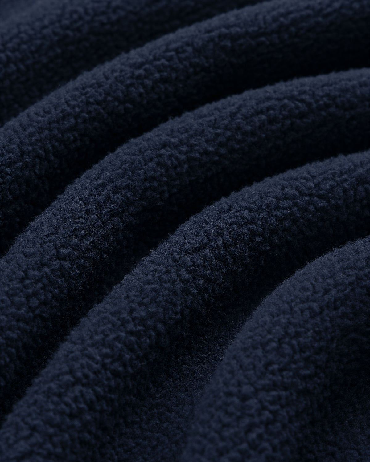 Close-up of Crest Quarter-Zip Fleece Pullover in dark blue, featuring curved ridges and a soft, textured surface.