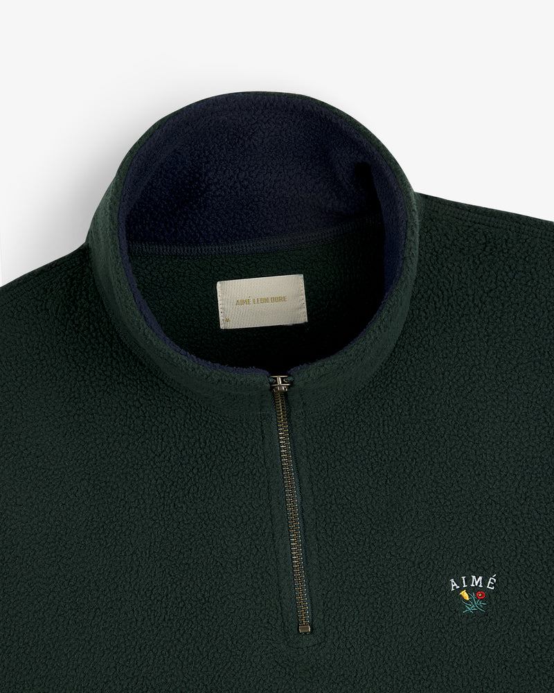 Crest Quarter-Zip Fleece Pullover in dark green with “AIMÉ” and a small flower embroidered on the chest.