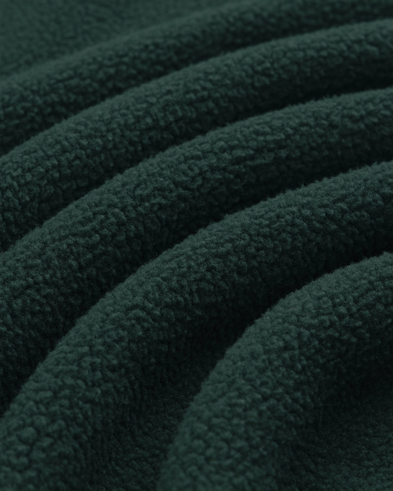 Close-up of Crest Quarter-Zip Fleece Pullover in dark green, highlighting its soft, textured surface and curved folds.