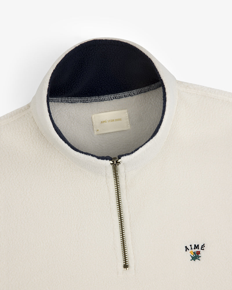 Crest Quarter-Zip Fleece Pullover in cream with navy collar lining and an AIMÉ floral chest logo.