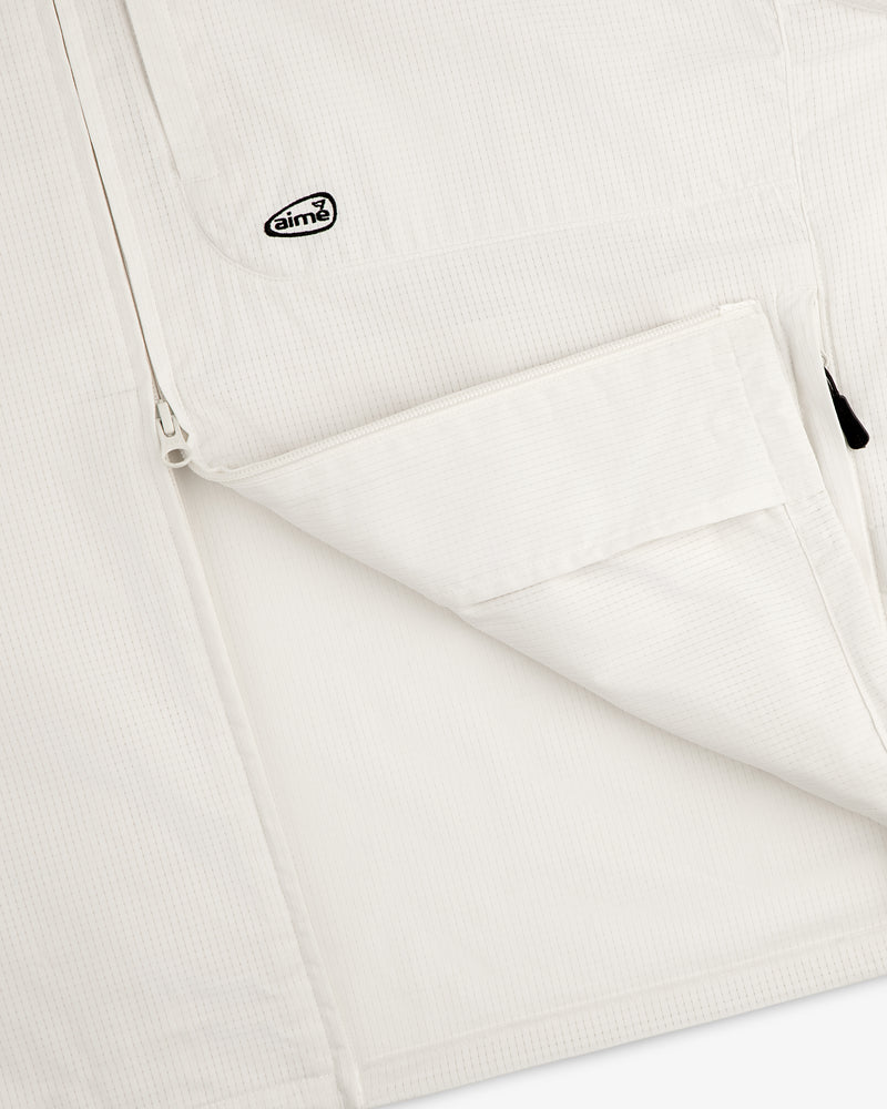 Close-up of the ALD Golf Lightweight Tips Windbreaker, featuring a white textured jacket with zip pocket and Aimé logo patch.