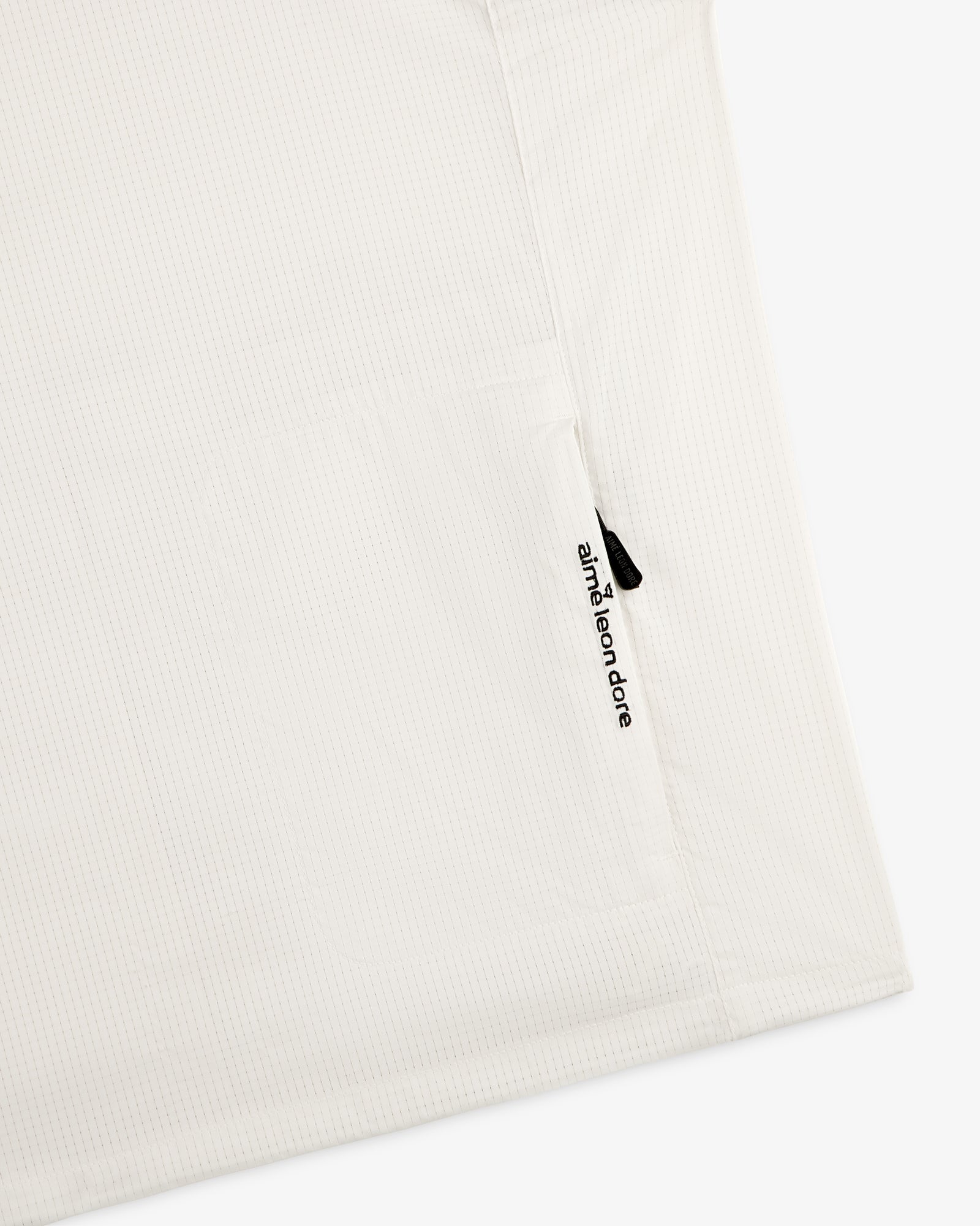 Close-up of the ALD Golf Lightweight Tips Windbreaker with a zippered pocket and branded zipper pull.