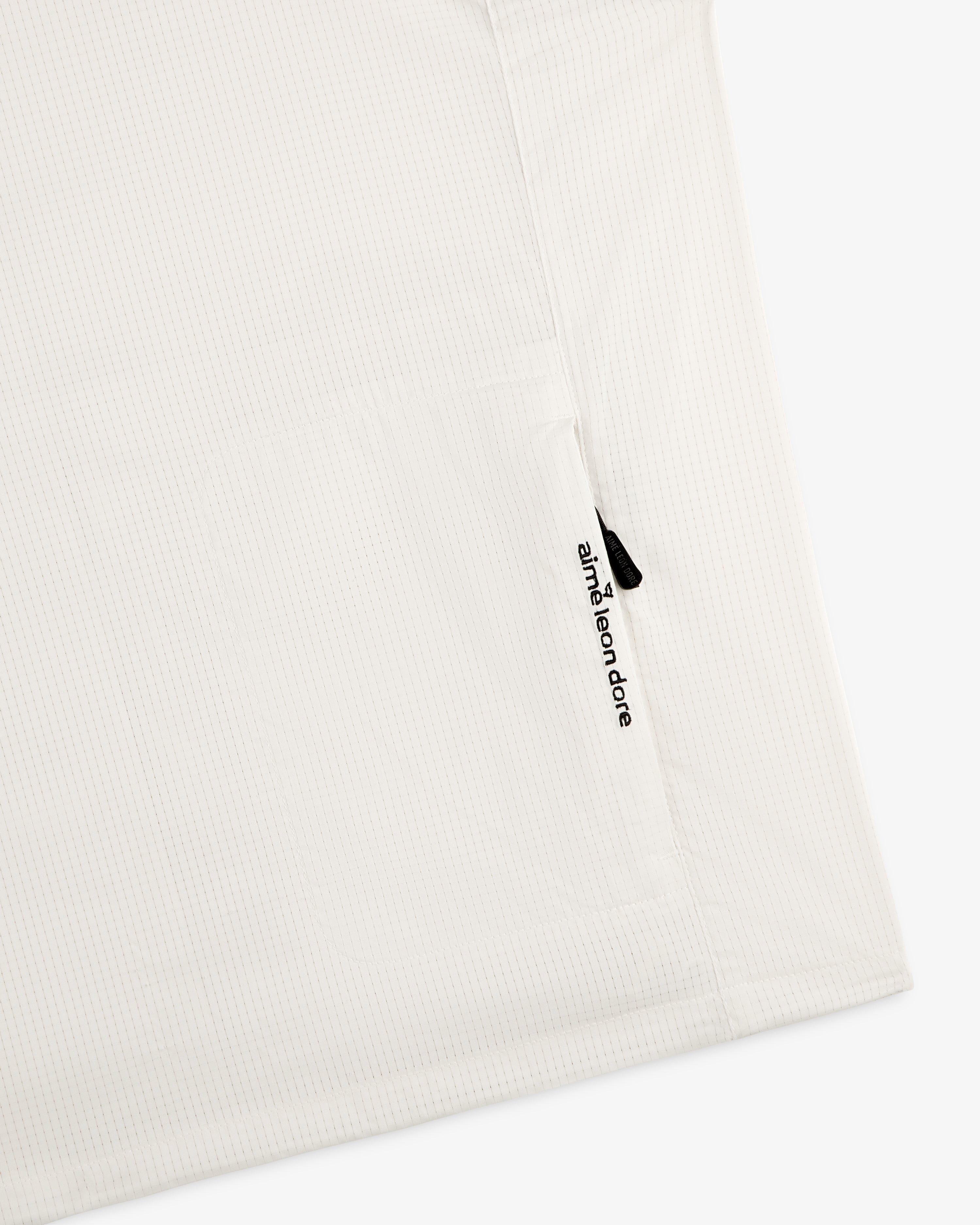 Close-up of the ALD Golf Lightweight Tips Windbreaker with a zippered pocket and branded zipper pull.