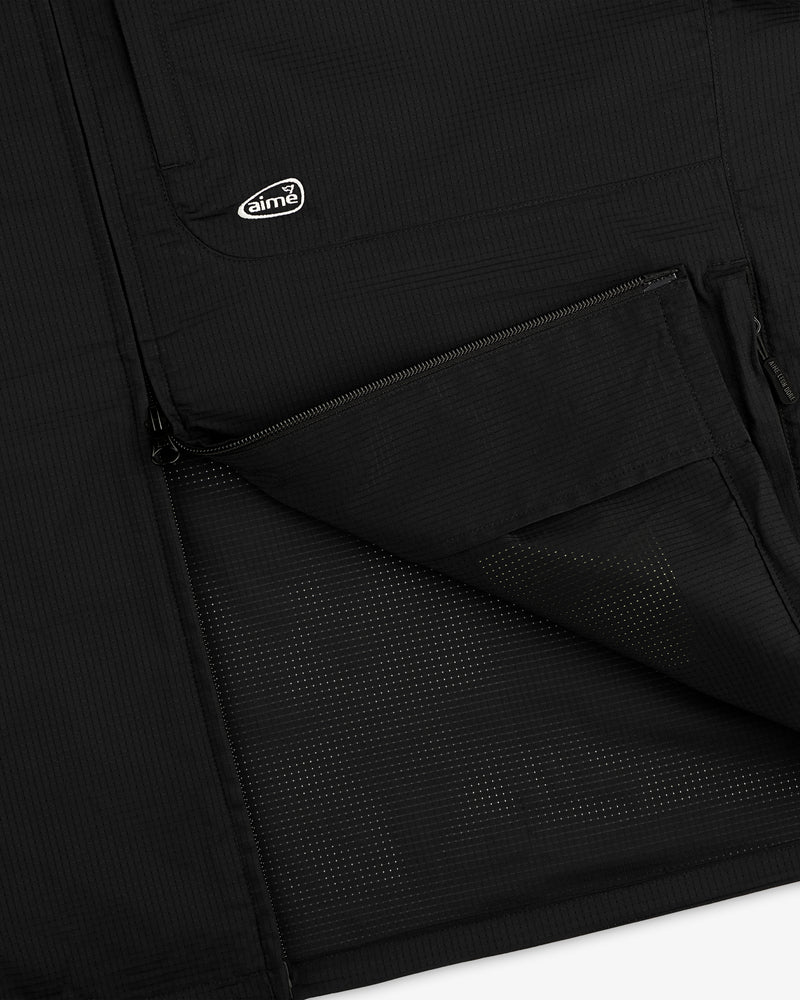 Close-up of ALD Golf Lightweight Tips Windbreaker in black with open zip pocket, mesh lining, and small aimé logo patch.