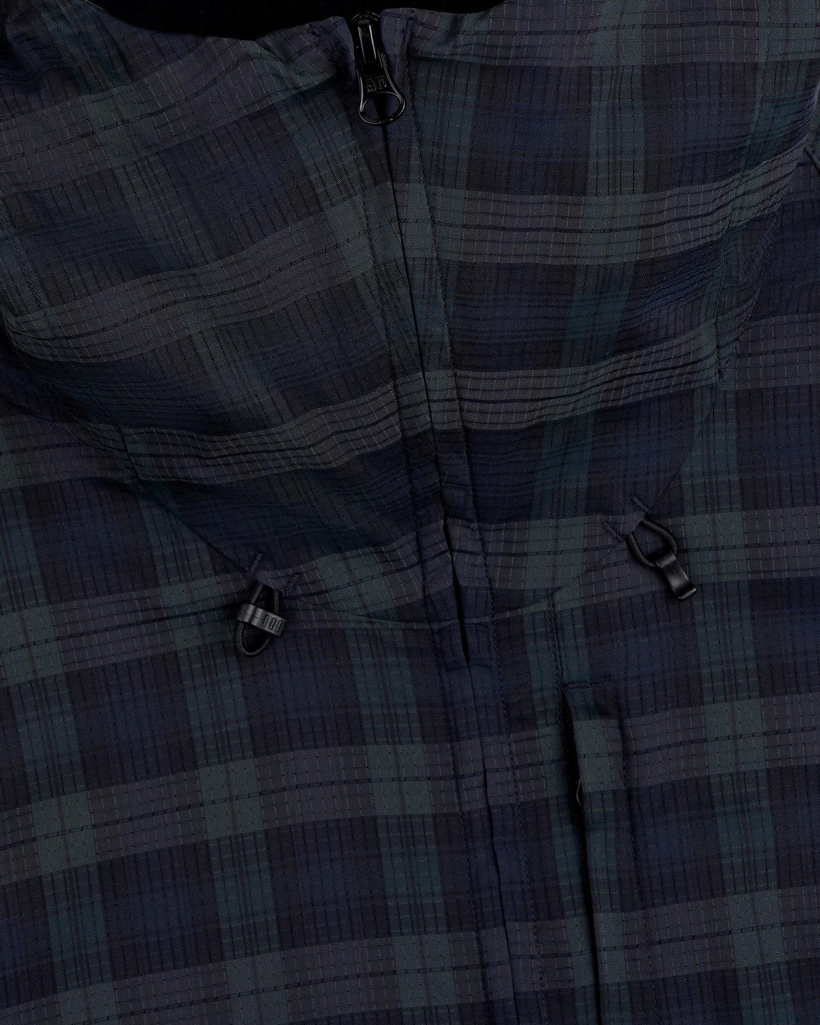 Close-up of the ALD Golf Lightweight Tips Windbreaker, featuring a plaid pattern, zipper, and two small black loops.