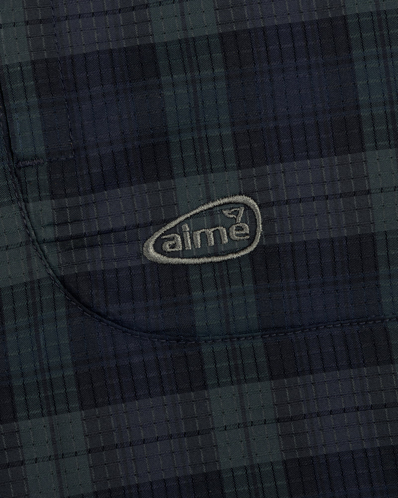 Close-up of a dark green and navy plaid ALD Golf Lightweight Tips Windbreaker with "aime" embroidered in light thread.