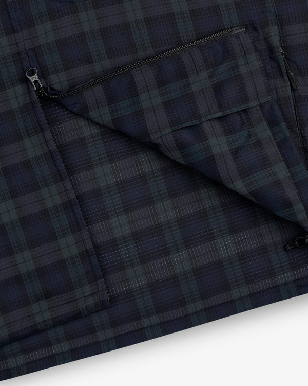 Close-up of the ALD Golf Lightweight Tips Windbreaker shows a dark plaid fabric with a partially open zippered pocket.