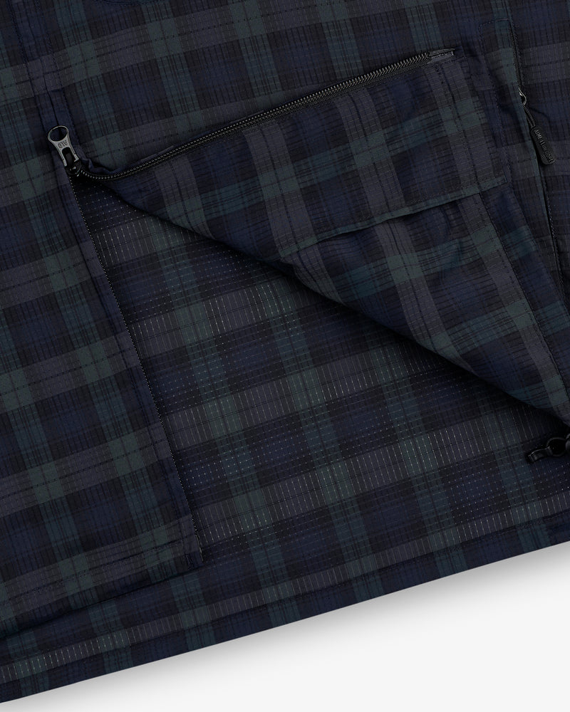 Close-up of the ALD Golf Lightweight Tips Windbreaker shows a dark plaid fabric with a partially open zippered pocket.