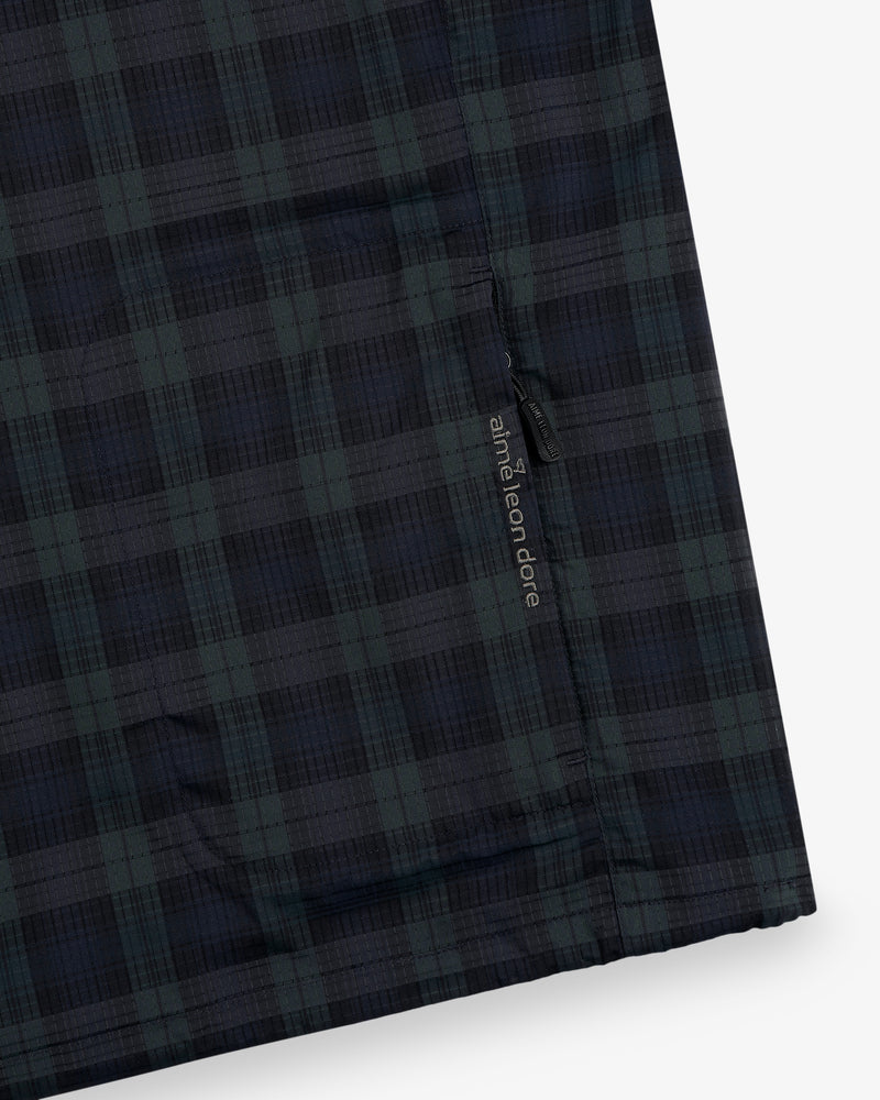 Close-up of the ALD Golf Lightweight Tips Windbreaker in dark blue and green plaid with a small black "and wander" tag.