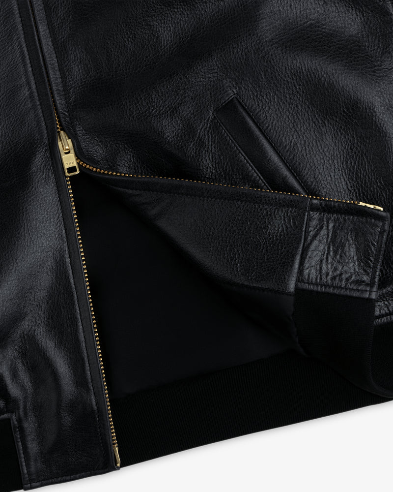 Close-up of the ALD / Technics Varsity Leather Jacket in black leather with a gold zipper, pocket, and ribbed hem.