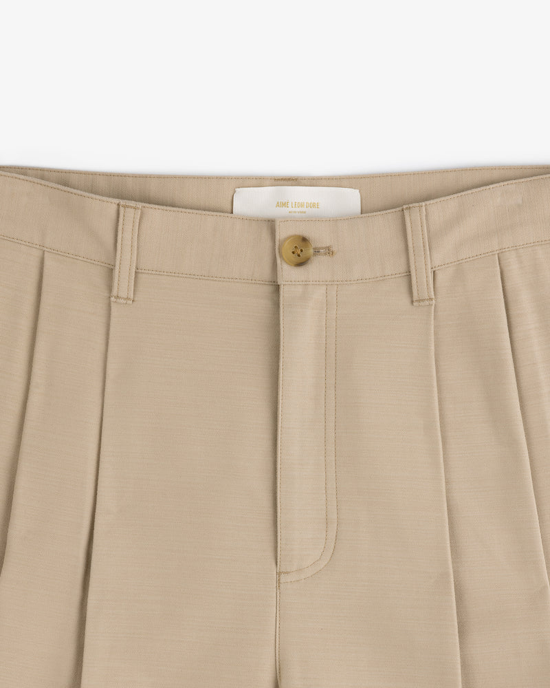 Close-up of Double Pleated Pant in beige featuring a button closure and detailed waistband.