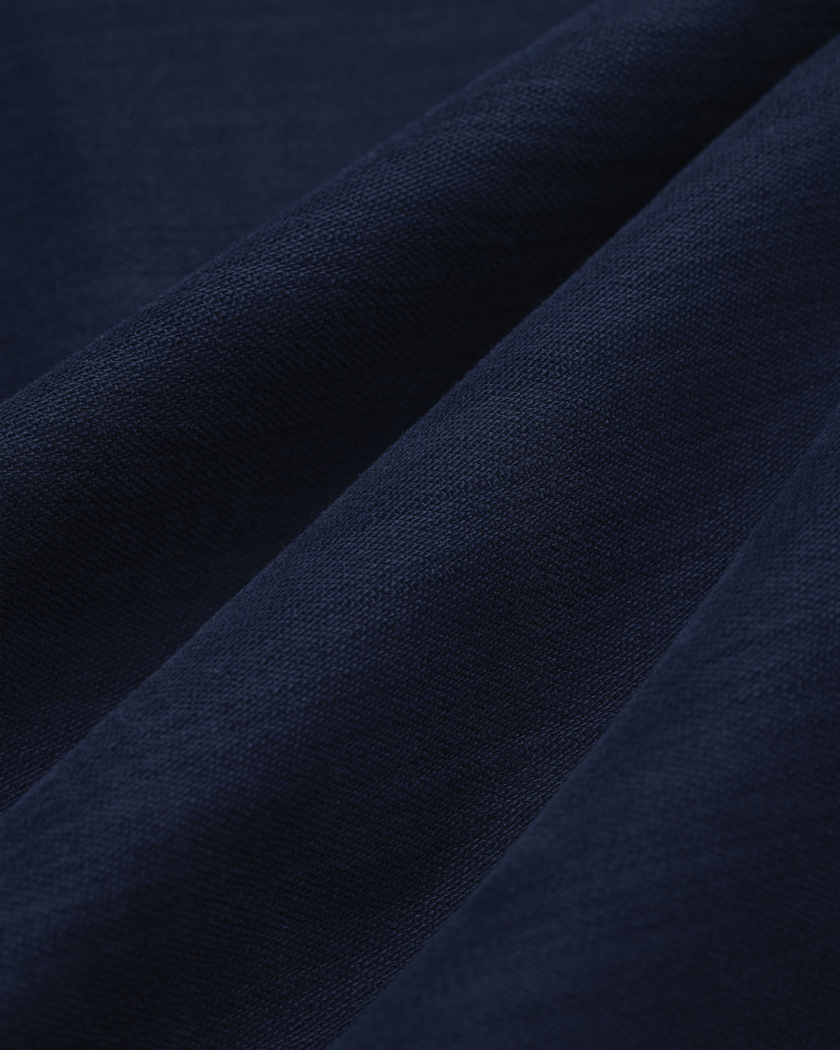 Close-up of Double Pleated Pant in dark blue, featuring textured fabric with soft folds and visible weave.