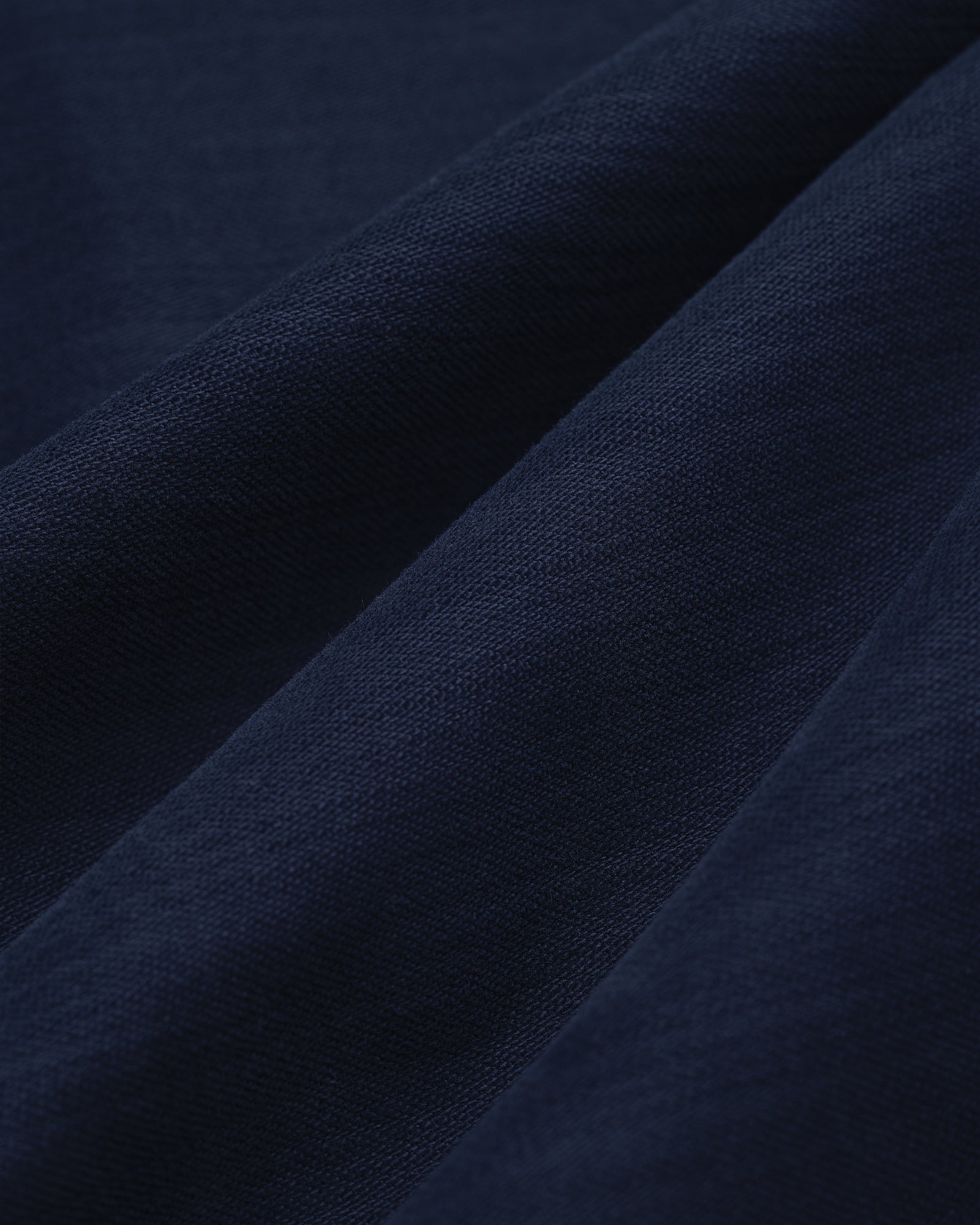 Close-up of Double Pleated Pant in dark blue, featuring textured fabric with soft folds and visible weave.