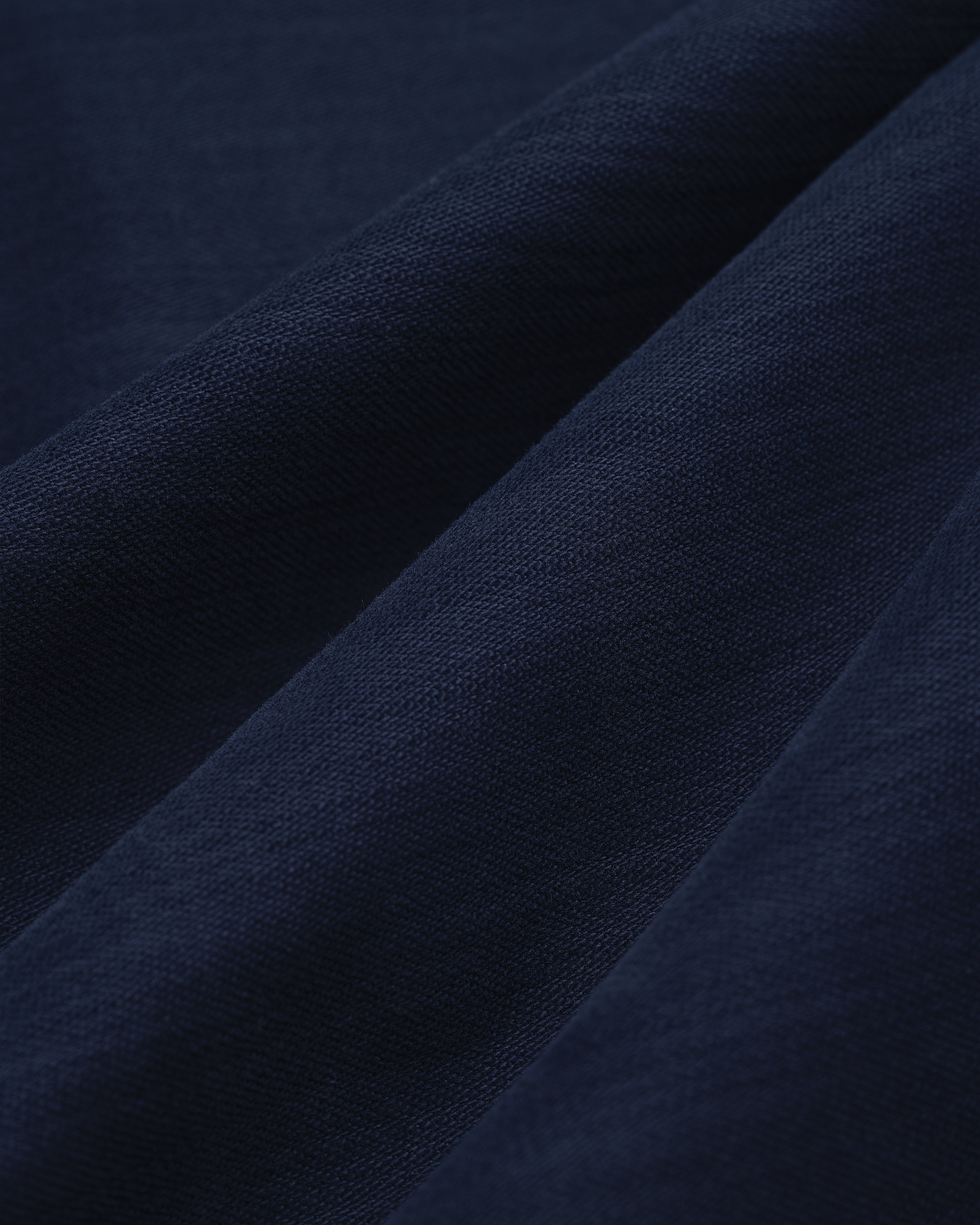 Close-up of Double Pleated Pant in dark blue, featuring textured fabric with soft folds and visible weave.