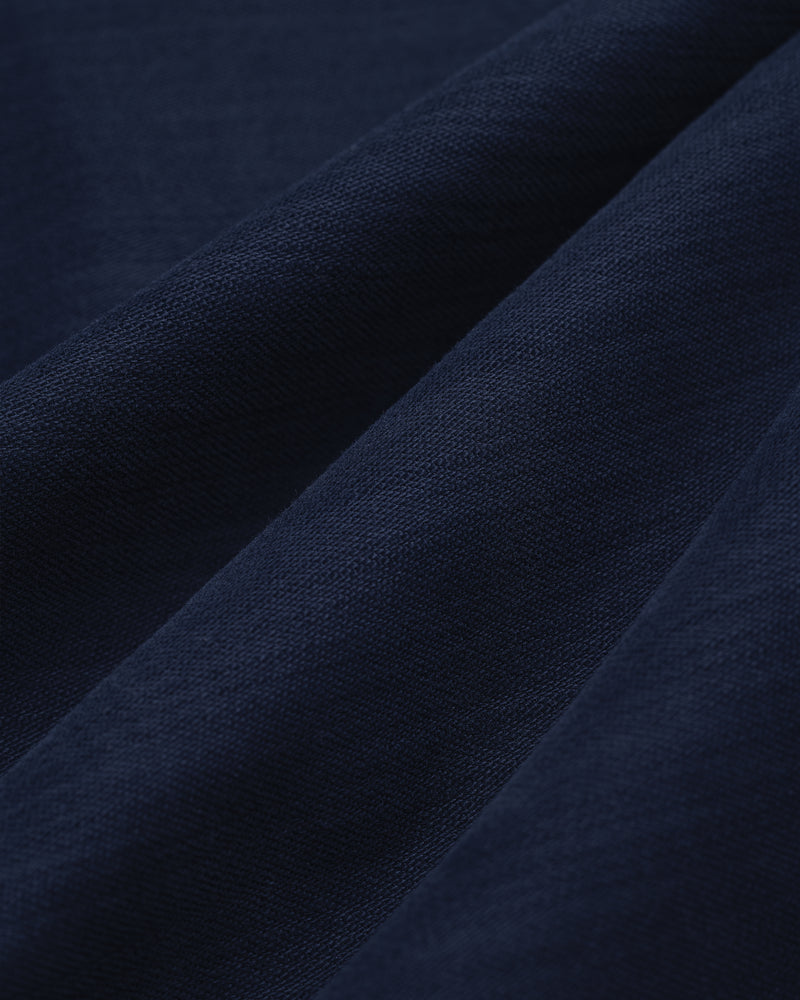 Close-up of Double Pleated Pant in dark blue, featuring textured fabric with soft folds and visible weave.