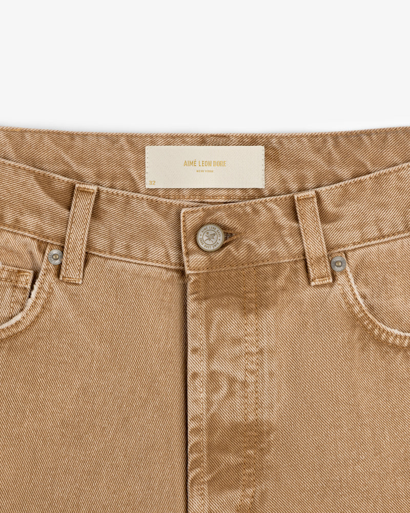 Close-up of Relaxed Fit 5-Pocket Denim Pant in tan with silver button and Aime Leon Dore label on the waistband.