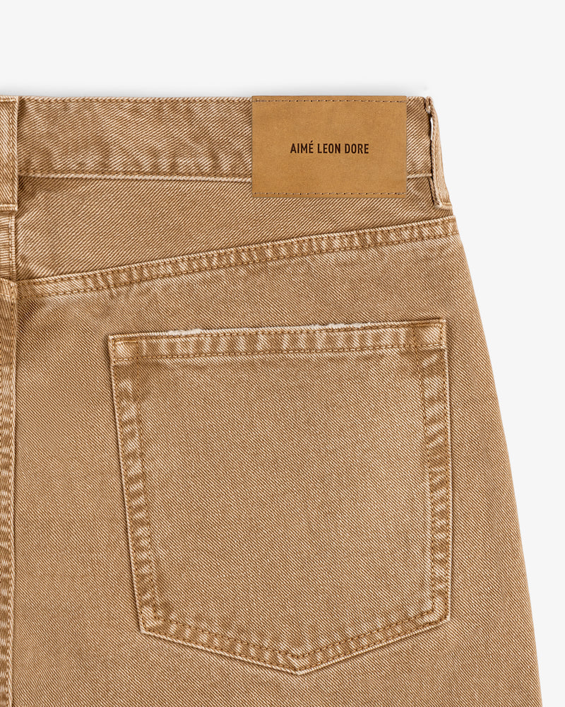 Close-up of the back pocket and tan leather patch on Relaxed Fit 5-Pocket Denim Pant in beige by AIMÉ LEON DORE.