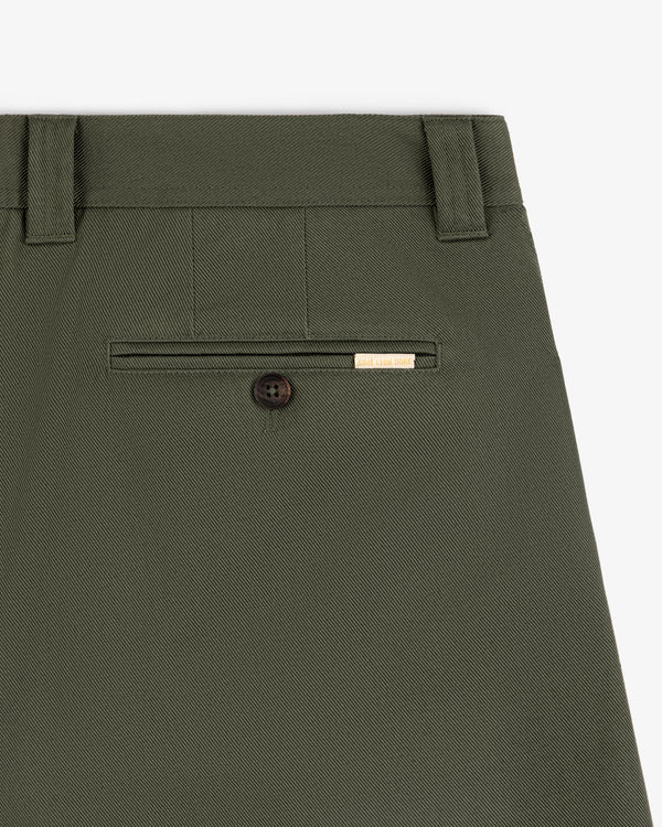 Close-up of Officer Pant in olive green, featuring a back pocket with button and a small gold label above it.