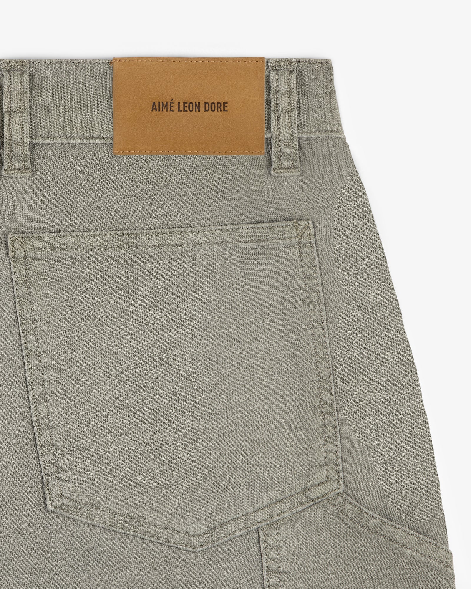 Close-up of Linen Blend Carpenter Pant in beige, showing a back pocket and AIMÉ LEON DORE leather patch on waistband.