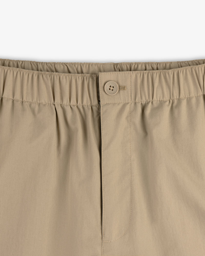 Close-up of Relaxed Cotton Trouser's beige waistband with elastic, button, and zipper fly.