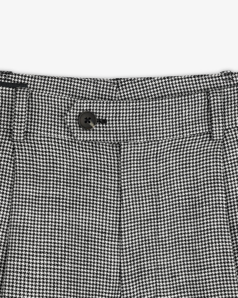 Close-up of the Houndstooth Pleated Trouser's black and white houndstooth waistband with a black button.
