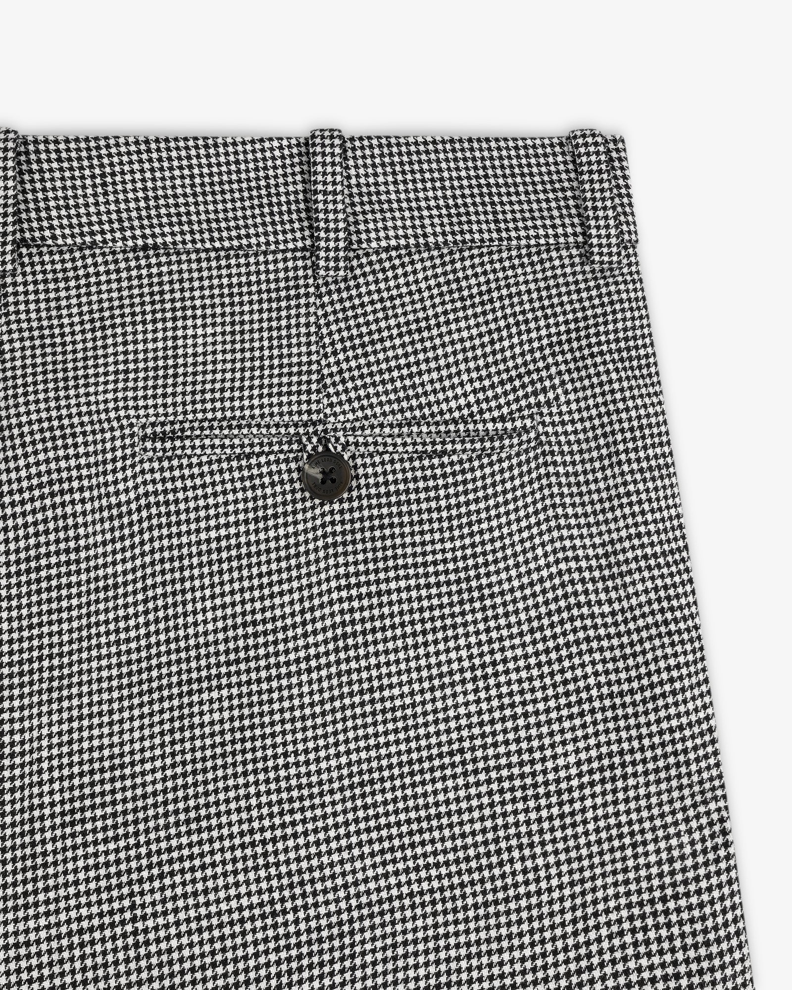 Close-up of Houndstooth Pleated Trouser in black and white with back pocket and black button.