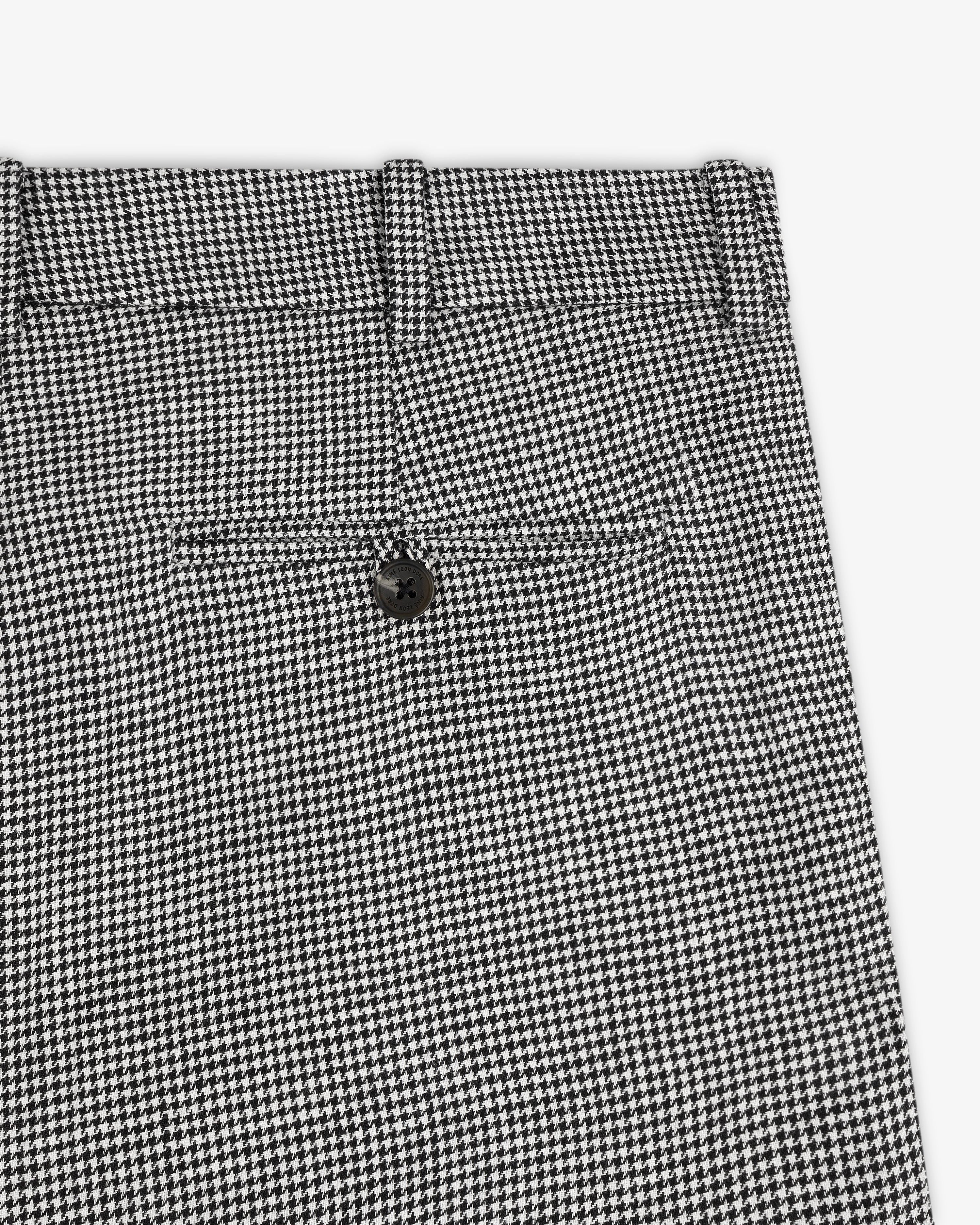 Close-up of Houndstooth Pleated Trouser in black and white with back pocket and black button.