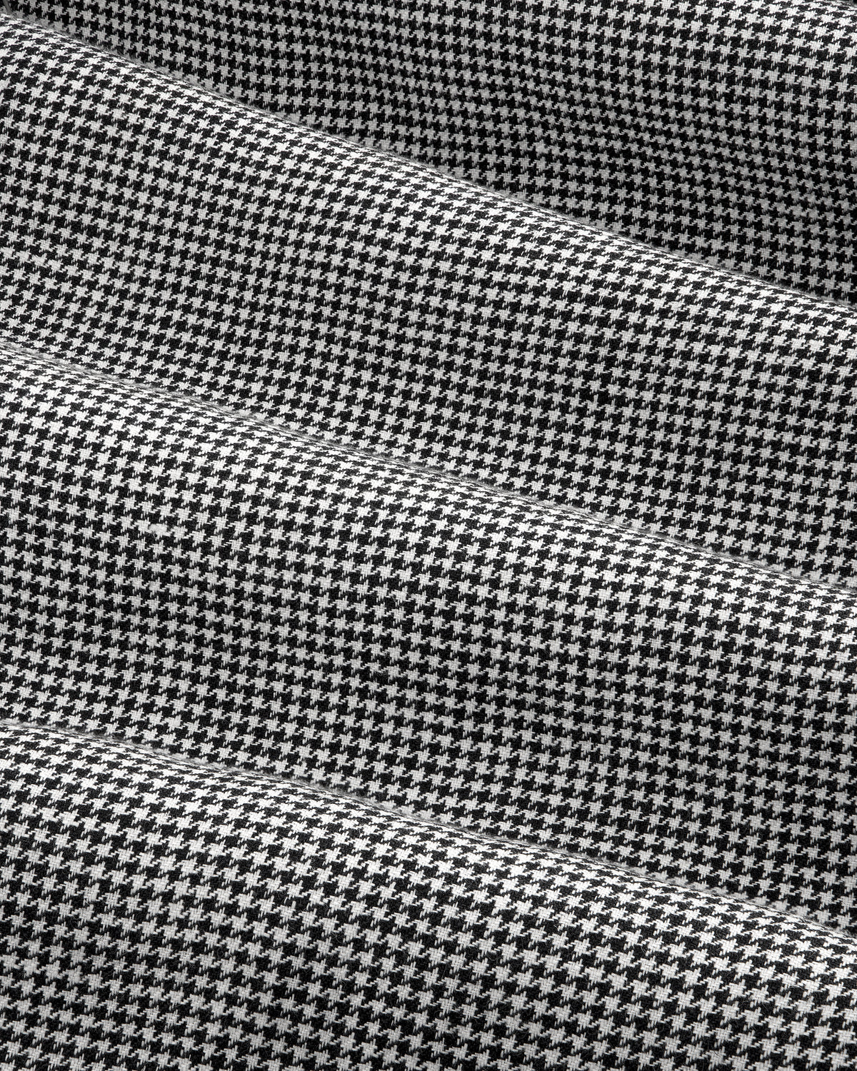Close-up of Houndstooth Pleated Trouser in black and white with subtle horizontal folds in the fabric.