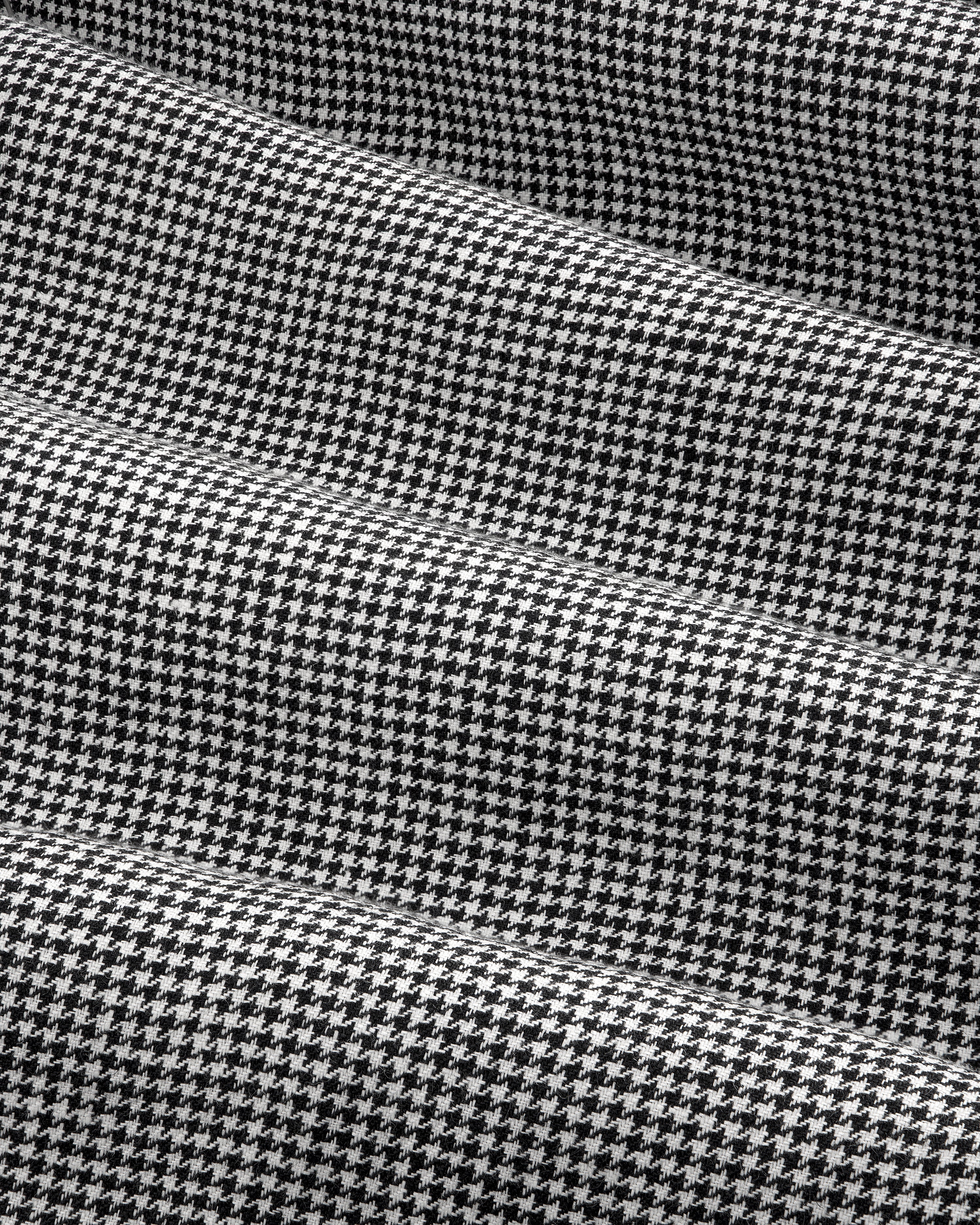 Close-up of Houndstooth Pleated Trouser in black and white with subtle horizontal folds in the fabric.