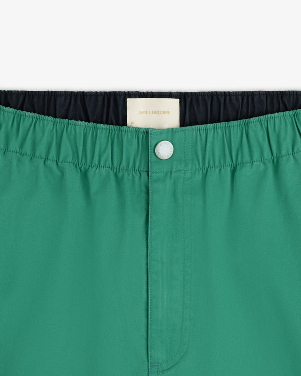 Close-up of Washed Cotton Windbreaker Pant in green with elastic waistband, white button, and inner label visible.