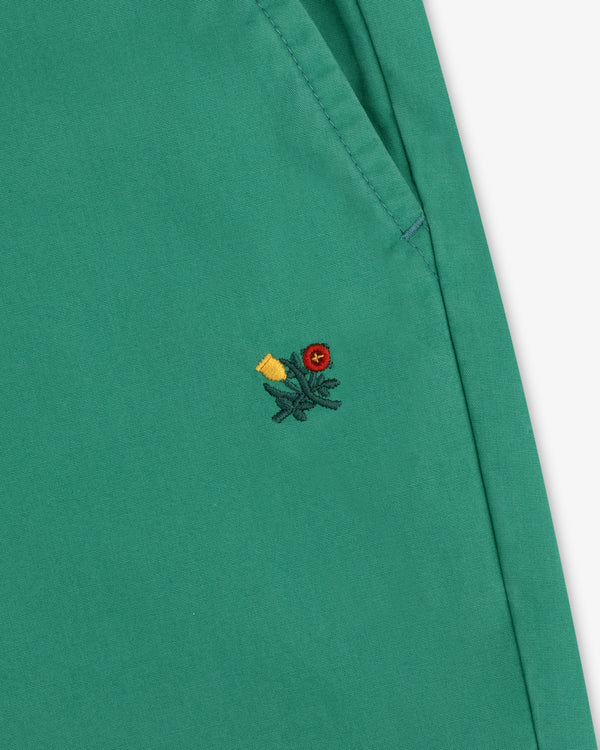 Washed Cotton Windbreaker Pant in green with visible stitching and a small embroidered floral detail near the seam.