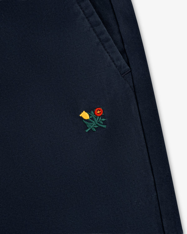 Close-up of Washed Cotton Windbreaker Pant in navy with a small yellow and red flower embroidered near the pocket seam.