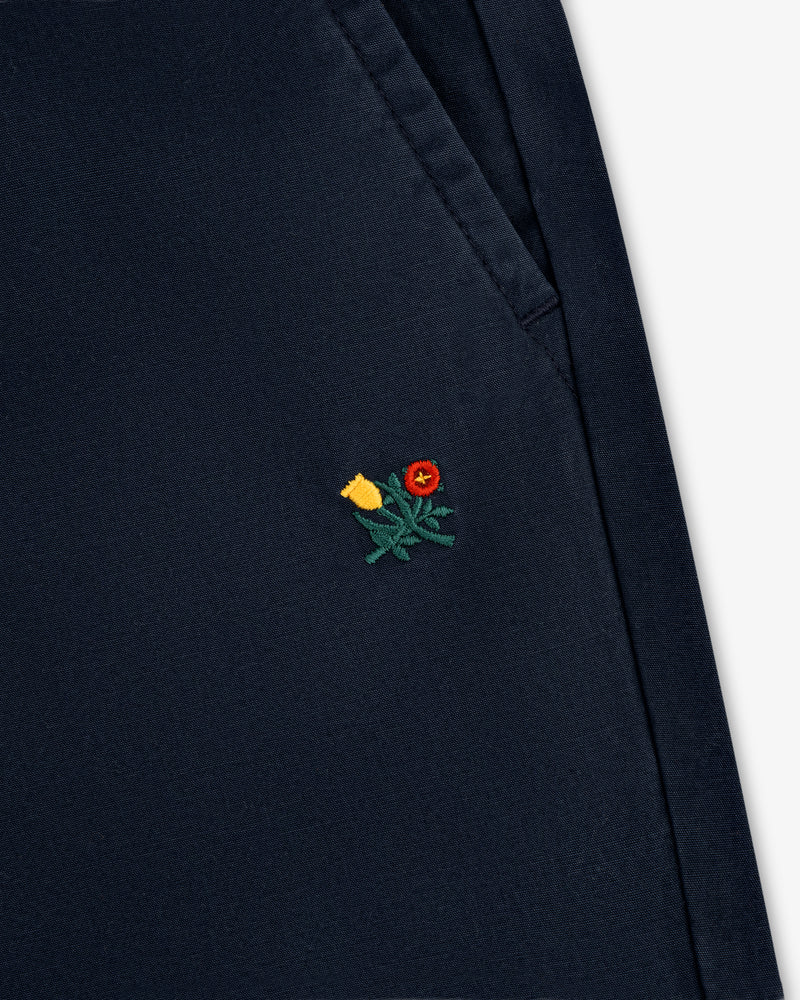 Close-up of Washed Cotton Windbreaker Pant in navy with a small yellow and red flower embroidered near the pocket seam.