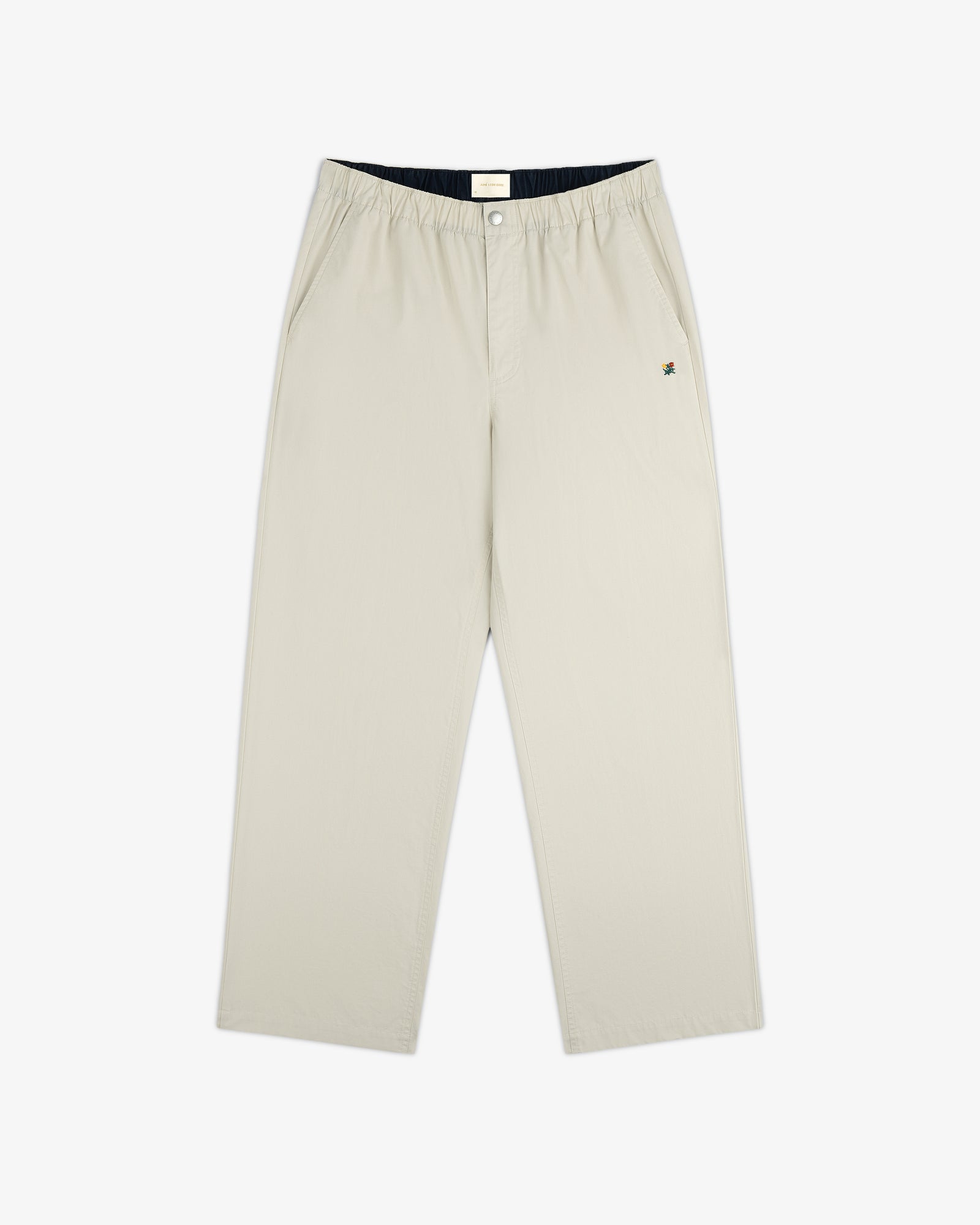 The Washed Cotton Windbreaker Pant features a beige, wide-leg design with an elastic waistband and side pockets.