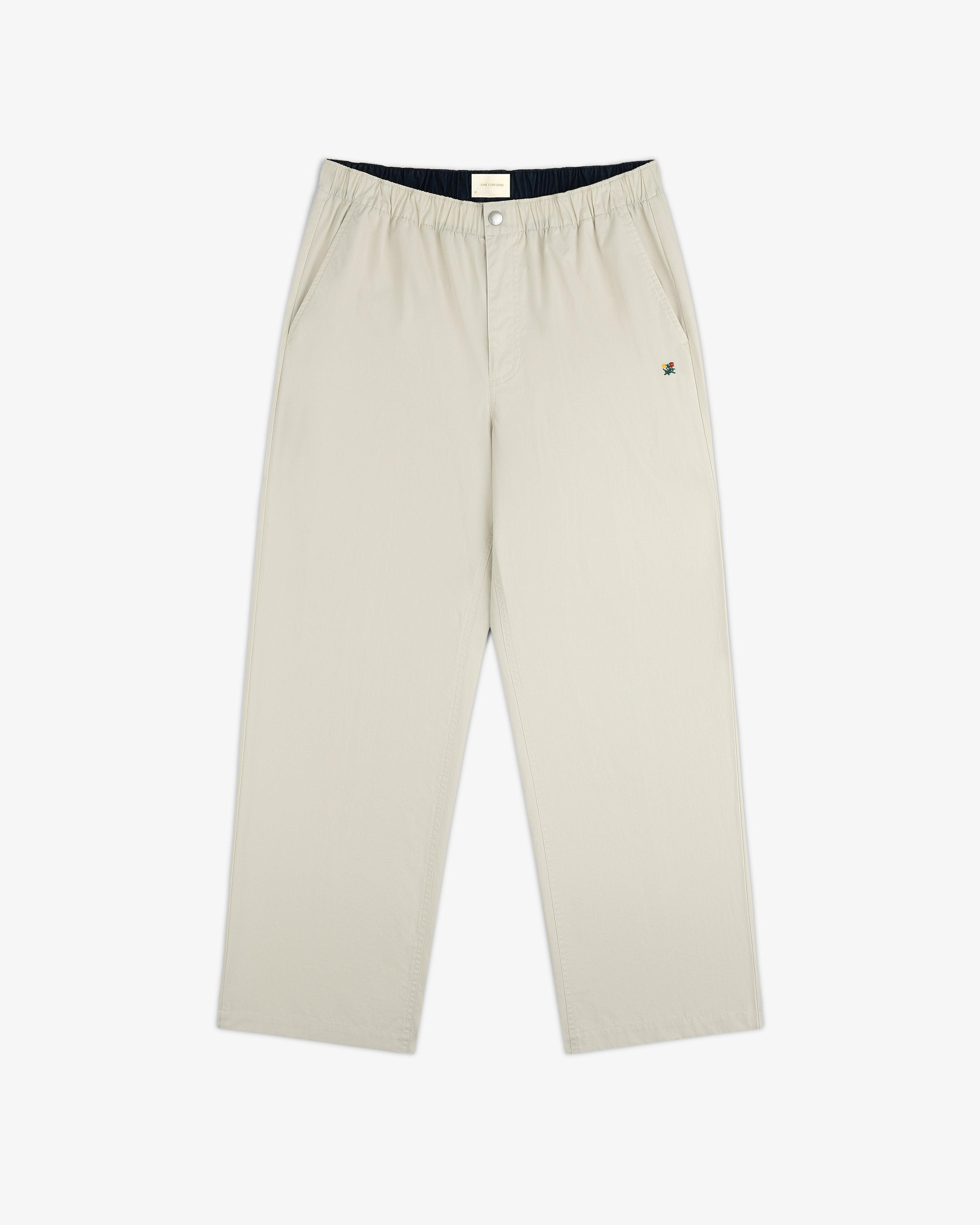 The Washed Cotton Windbreaker Pant features a beige, wide-leg design with an elastic waistband and side pockets.
