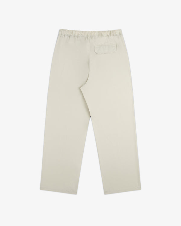 Washed Cotton Windbreaker Pant in beige with elastic waistband and one back pocket, shown flat on white.