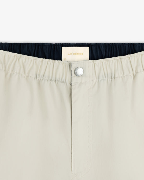 Close-up of Washed Cotton Windbreaker Pant waistband with a silver button and white Aimé Leon Dore label inside.