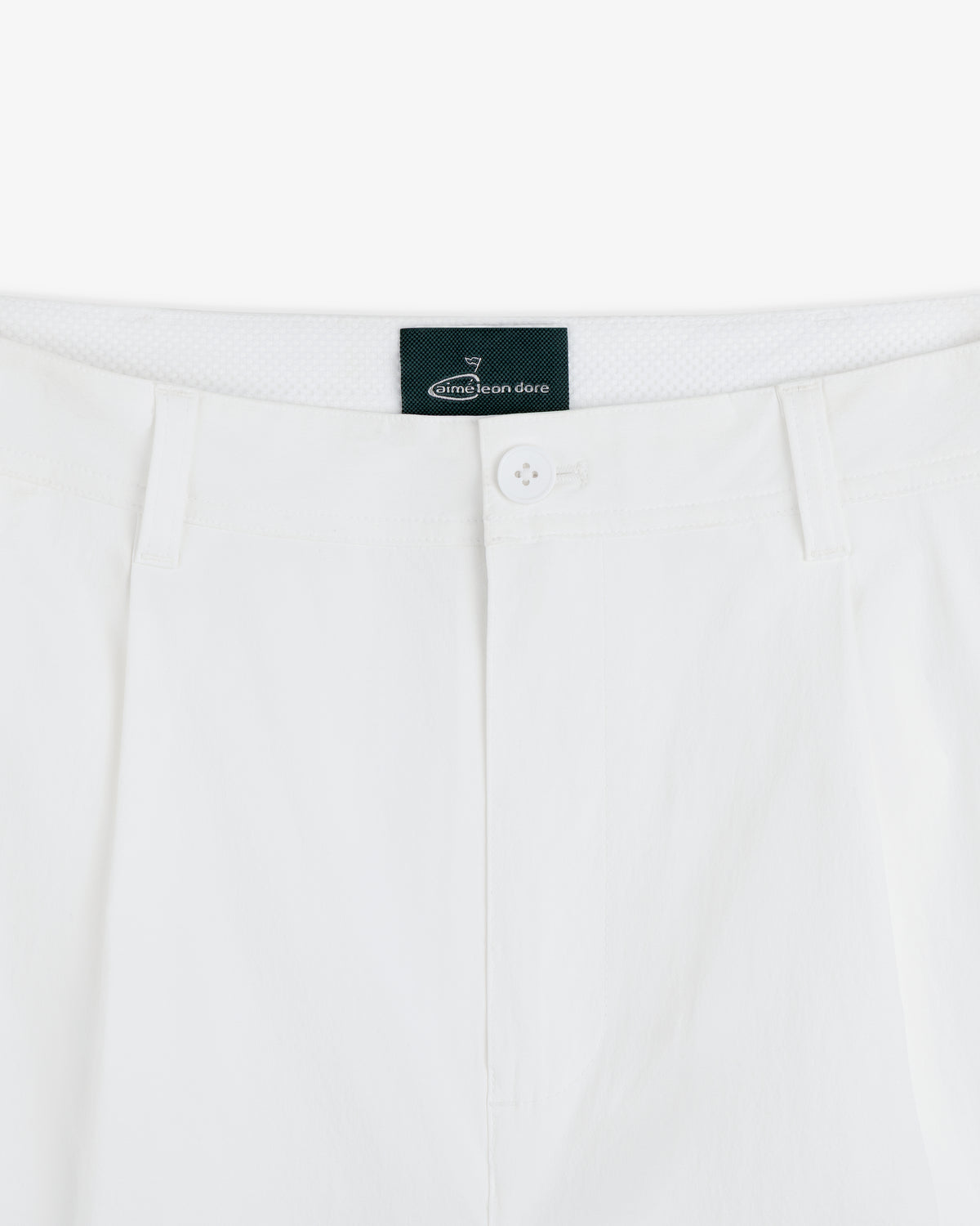 Close-up of the waistband and button of white ALD Golf Cordura Double Pleated Pant with black Aimé Leon Dore label inside.