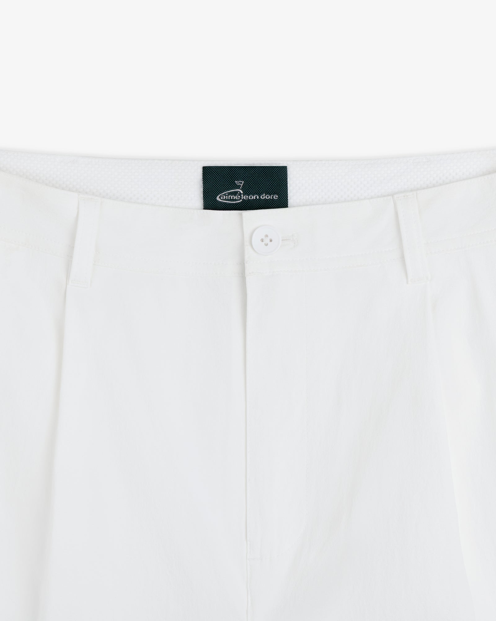 Close-up of the waistband and button of white ALD Golf Cordura Double Pleated Pant with black Aimé Leon Dore label inside.
