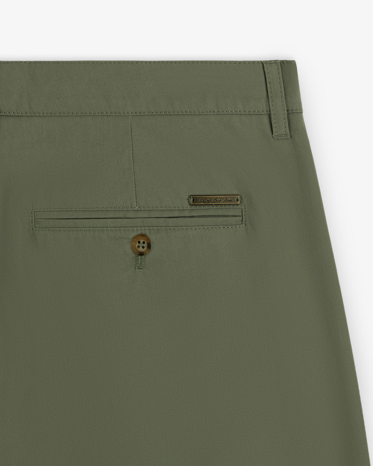 Close-up of Lightweighted Pleated Cotton Trouser in olive green with a buttoned back pocket and metallic brand tag.